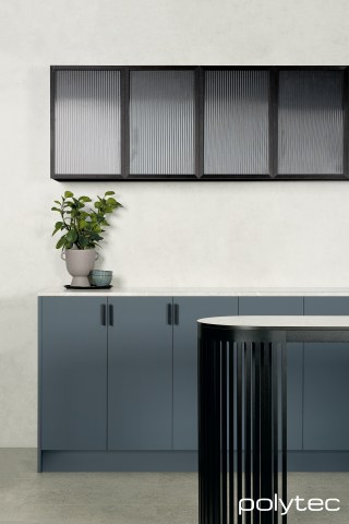 polytec KITCHEN - Cabinets in Habitat Venette, 21mm Tightform Benchtop in Portofino Stone Smooth, Splashback in White Cement Smooth, Island benchtop in Compact laminate  in Tivoli Ceppo Smooth, Overhead Cabinets in 23mm Brushed Black Frame,  with Fluted Glass Insert.
